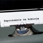 Kartka wystająca ze starej maszyny do pisania z komunikatem: "zaproszenie na komisję".