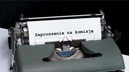 Kartka wystająca ze starej maszyny do pisania z komunikatem: "zaproszenie na komisję".