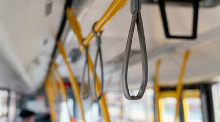 Zdjęcie wnętrza autobusu - widoczne poręcze i uchwyty do trzymania.